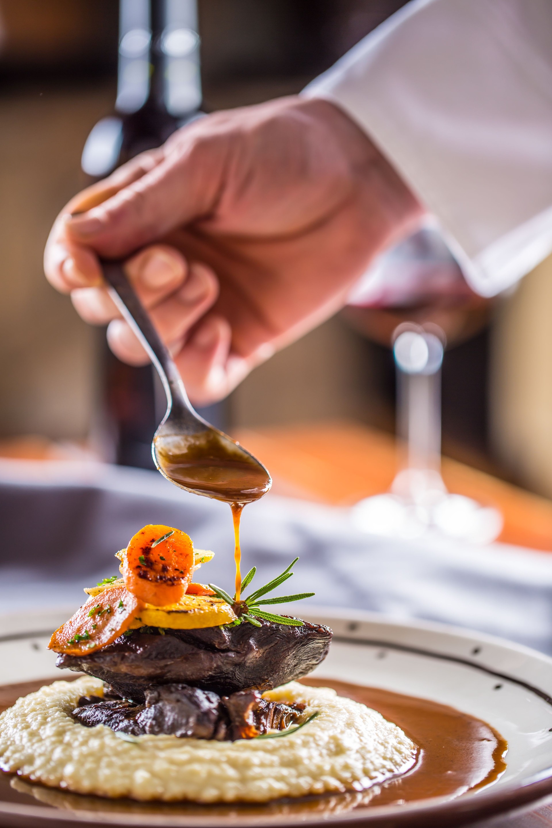 Chef in pub or restaurant decorates portion of the meal in pup or restaurant